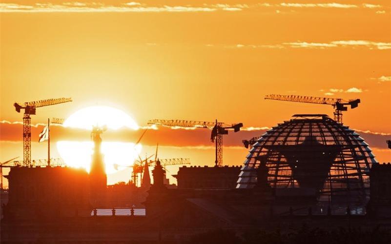 Baukräne und die Kuppel des Reichstagsgebäudes in Berlin. Die deutsche Wirtschaft kommt wieder in Schwung. Foto: Fabian Sommer/dpa