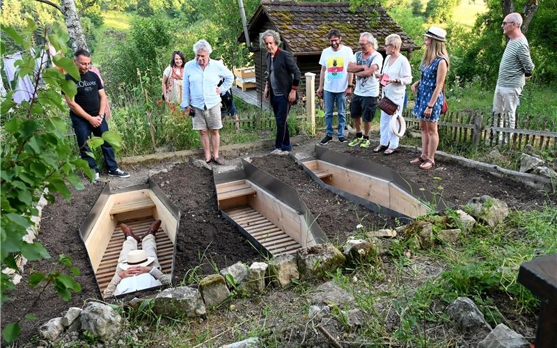 Blick aus der Erde in den Himmel: Auf dem „Internationalen Testfriedhof“ von Daniel Schürer (Mitte, in Schwarz) steigen seit Beginn des Sommers immer wieder Neugierige in die sargähnlichen Konstruktionen hinab und lassen dies wirken. GB-Foto (Archiv): Holom