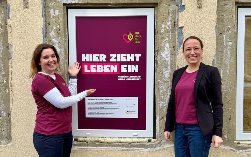 Carolin Fenchel (links) und Mara Meinkuss stellen das erste „Coming-soon-Plakat“ der Initiative „Mit Herz für Hier“ vor. Es häng in einem Fenster des ehemaligen Foto-Markts in der Schulstraße und informiert schon einmal über den künftigen Mieter – „Lafan Fashion“.GB-Fotos: Denu
