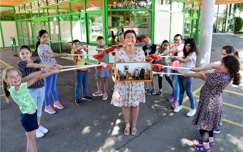 Die Drittklässler machen einen „Kehraus“ für Rektorin Waltraud Oelkuch-Philipsen, die in ihren Händen ein Miniatur-Klassenzimmer mit Steiff-Bären trägt GB-Foto: Holom