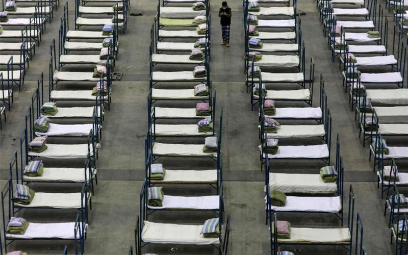 Ein Mitarbeiter steht zwischen Feldbetten, die in einem Kongresszentrum in Wuhan aufgestellt wurden. Es fehlen Betten zur Behandlung von Infizierten. Foto: -/CHINATOPIX/AP/dpa