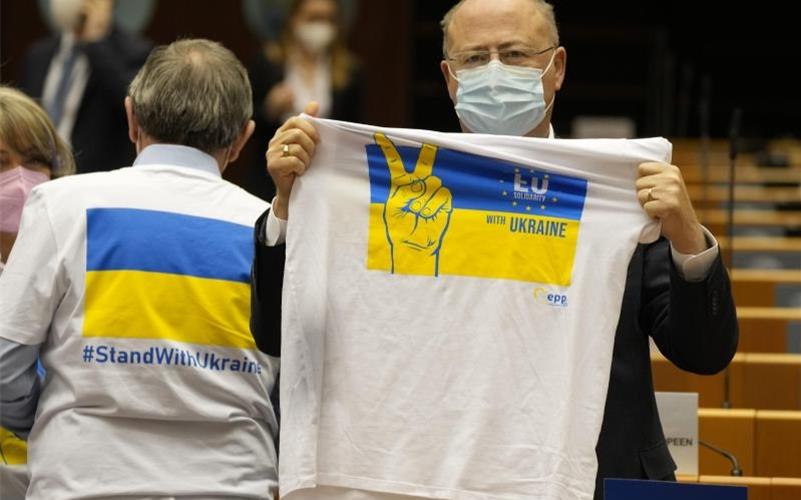 Ein Mitglied des Europäischen Parlaments hält ein T-Shirt in den Farben Blau und Gelb zur Unterstützung der Ukraine. Foto: Virginia Mayo/AP/dpa
