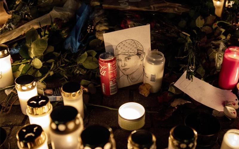 Ein gezeichnetes Porträt, Blumen und Kerzen liegen an einer provisorischen Gedenkstätte, wo der schwedische Rapper Einar 2021 erschossen wurde. Foto: Christine Olsson/TT NEWS AGENCY/AP/dpa