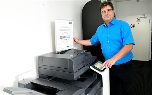 Hans-Joachim Schrock mit dem Zertifikat an einem der ausgetauschten DruckerGB-Foto: Holom
