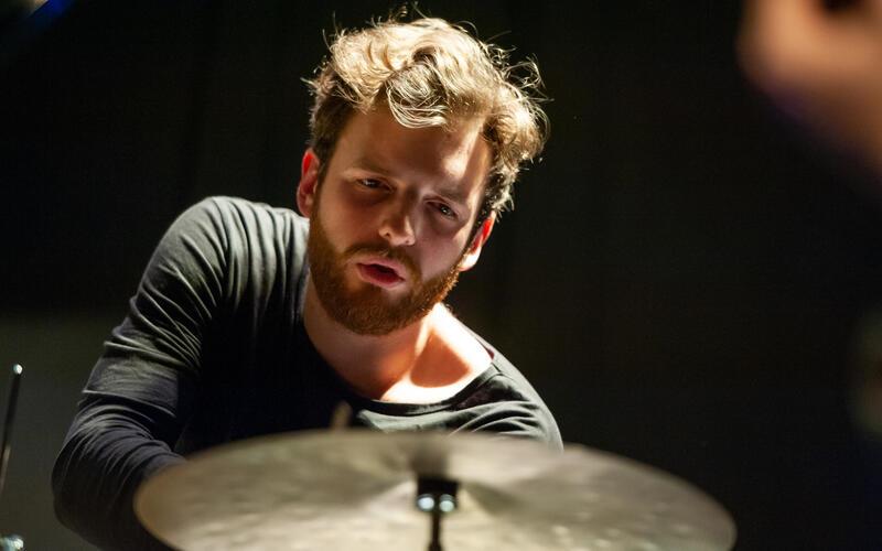 Herrenberg – Lucas Johnson, 31 Jahre alt, ist in der Jazzszene ein gefragter Musiker. Mit seinem 2018 veröffentlichten Debütalbum wurde er zum Kulturbotschafter des Jazzverbands Baden-Württemberg und vertrat das Land auf der internationalen Musikmesse JazzAhead in Bremen. Nun legt er mit seiner 2010 gegründeten Band „nju:zone“ nach drei Jahren Vorbereitungszeit sein zweites Album vor. In dessen Titel „Homecoming“ spiegeln sich auch die Gefühle, die der zwischen Berlin und Herrenberg pendelnde Drummer hat, wenn er zurückkehrt in seine Heimat. „Einige der Songs sind während der Pandemie entstanden, der Pop-Approach mit eingängigen Melodien war mir ganz wichtig, ebenso das Zusammenspiel der Musiker und Instrumente. Das neue Album sollte nicht mehr so jazzlastig sein wie das erste, Soli sind dabei in die Kompositionen eingearbeitet, im Studio kamen nachträglich noch Overdubs mit Synthesizer und Percussion hinzu“, sagt Lucas Johnson. Mit dabei sind Alex Ventling, ein aktuell im norwegischen Trondheim lebender Neuseeländer, Fabian Willmann an Tenor-Saxophon und Bassklarinette, Igor Osypov an den Gitarren und der aus Horb stammende und in London lebende Bassist Niklas Lukassen. Als Gast ist noch der Trompeter Dima Bondarev mit dabei. „Meine Vision war, über Genregrenzen hinauszugehen und eine neue Art von Jazzmusik zu schaffen“, so Johnson über seine Form von Hybrid-Jazz. Am Freitag, 29. Mai, um 20 Uhr stellen „nju:zone“ die neue Platte nun erstmals im Mauerwerk Herrenberg vor. tv/GB-Foto: Susanne Drescher
