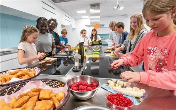 In der Schulküche bereitet die Bläserklasse zusammen mit ihren Besuchern aus Kenia, Kinderhausleiterin Eunice Okore (Dritte von links) mit ihrer Tochter Anthea Anjango (zweite von links), afrikanische Snacks zu. GB-Foto: Vecsey