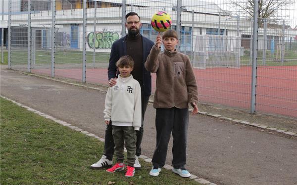 Nathanael Bader setzt sich mit seinen Söhnen David (rechts) und Jonte dafür ein, dass es mehr Begegnungsmöglichkeiten für Familien gibt. Im Hintergrund ist der bei der Realschule gelegene Bolzplatz zu sehen, der zuletzt geschlossen war. GB-Foto: Bäuerle