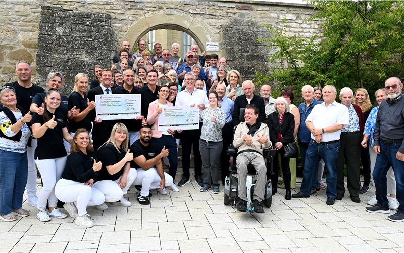 Rund 40 Zahngoldspender kamen am Freitag in die Zahnarztpraxis Dr. Platten/Dr. Knapp nach Nufringen. Gemeinsam mit dem Team übergaben die Dentalmediziner vor der Pelagiuskirche zwei symbolische Spendenschecks: Einen über 100000 Euro an den Förderkreis krebskranke Kinder für das „Blaue Haus“ in Stuttgart, einen weiteren über 17986 Euro für Alex Efstathious „Kinderherzaktionen“. Dabei handelt es sich um den Erlös aus dem Verkauf von gespendetem Zahngold Dutzender Patienten. GB-Foto: Holom