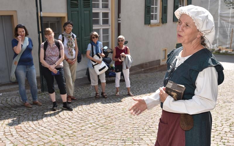 Sonja Klaus Condo (im historischen Gewand) weiß beim ehemaligen Spital Interessantes zu berichten GB-Foto: Vecsey