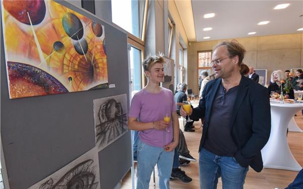 Viele Besucher in der Volksbank Entringen bei der Eröffnung der Ausstellung. Die Art-Road-Way Kunstschule Breitenholz hat junge Menschen aufgerufen, zu malen, was sie bewegt. Links: Paolo Breuninger vor seinen Bildern. GB-Foto: Vecsey