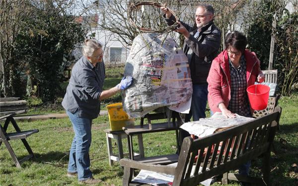 Vorbereitung für den Passionsweg im Dorf, Jona Mack-Stickel gestaltet mit Pappmache den Kopf von Christus, auf den dann Oliver Dersch die Dornenkrone legt und Ursula Gerlach mit Kleister Zeitungsseiten einschmiert. GB-Foto: Bäuerle