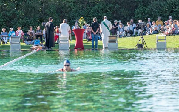 Während Schwimmer im Naturbad ihre Bahnen ziehen, zelebrieren die Vertreter der Kirchen auf dem Trockenen einen Gottesdienst.GB-Foto: Vecsey