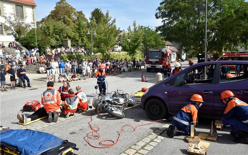 Während die Jugendfeuerwehr damit beschäftigt ist, die Hebekissen unter dem Auto zu platzieren, um die eingeklemmte Sozia zu befreien, kümmert sich das Jugendrotkreuz um die verletzte Motorradfahrerin. GB-Foto: Reichert