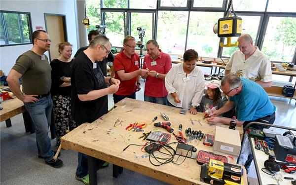 Zur Eröffnung des neuen Repair-Cafés in Bondorf im Werkraum der Grundschule bemühen sich die Ehrenamtlichen um die ersten Kunden Simon Kreidler (rechts) und Töchterchen Alessia, deren Prinzessinnen-Diadem repariert wird. GB-Foto: Holom