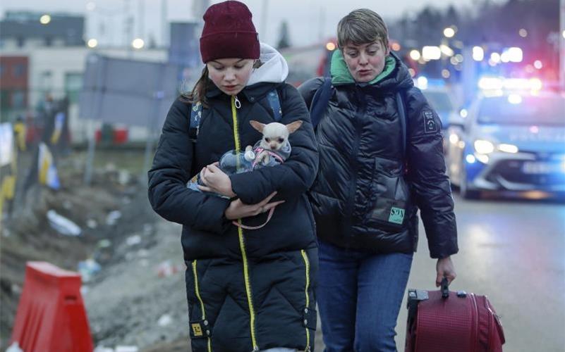 Zwei geflüchtete Frauen kommen mit einem Hund am Grenzübergang Medyka in Polen an. Foto: Visar Kryeziu/AP/dpa